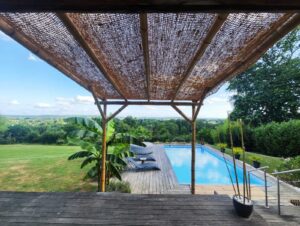 Une pergola Coco & Bambou autoportée avec ombrage naturel, parfaitement intégrée à une terrasse avec piscine.