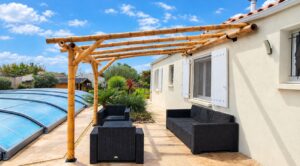 Vue rapprochée d'une pergola adossée en bambou Guadua avec poteaux, jambes de force, traverses et fixations murales.