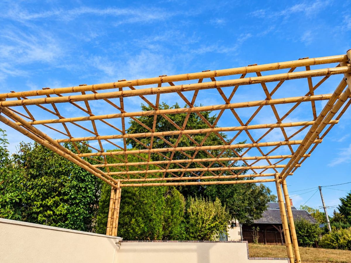 Vue en contre-plongée de la charpente d'une pergola en bambou, montrant les poutres, les traverses et les éléments de renfort de toiture.